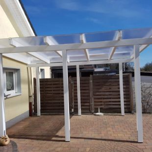 Pergola (Carport) in weiß von der Seite an einem Haus